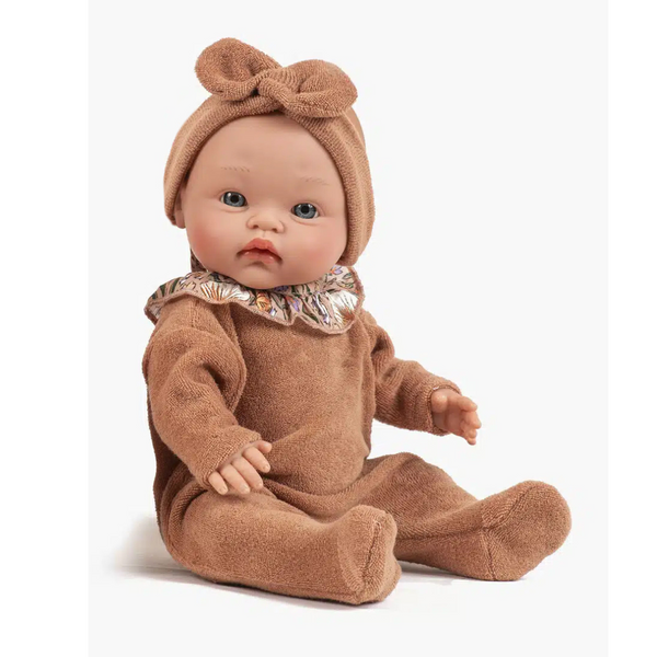 US stockist of Minikane's Iris Cuties doll dressed in a brown sugar sleepsuit with ruffled Nausicaa collar and matching headband.